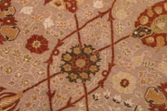 A close-up of a patterned textile or rug showing a beige background with red, rust, olive green, and cream floral and geometric motifs.