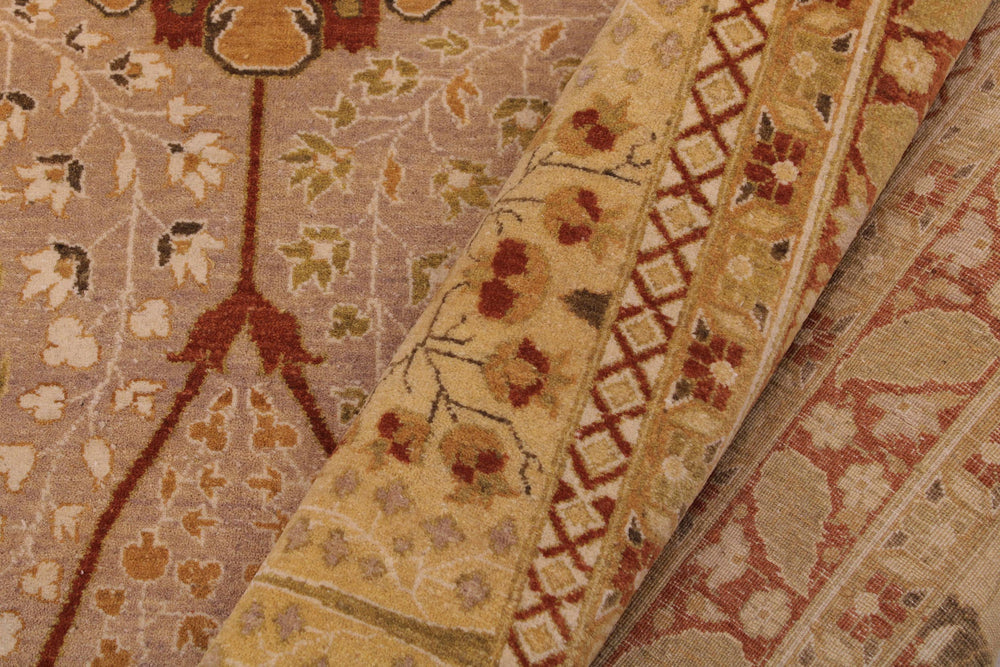 A close-up of a patterned area rug showing its detailed woven texture and traditional motifs in beige, rust red, and muted green.